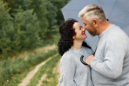 Photo for Close up romantic couple kissing in an autumn park. Man and woman wearing blue sweaters. Woman is brunette and man is gray. - Royalty Free Image