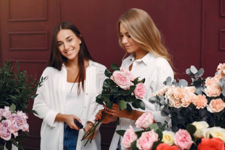 Florisr mit Blumen. Frauen machen einen Strauß. Zwei Mädchen arbeiten