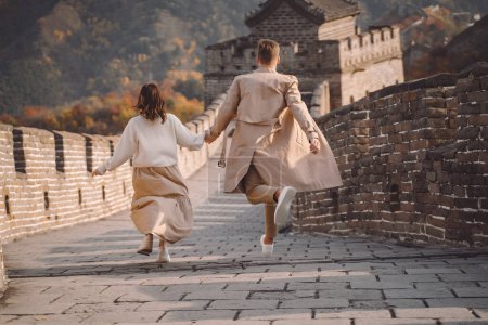 schönes junges Paar rennt und springt an der großen Mauer aus China. frisch verheiratete Paare auf ihrem Hochzeitsmarsch zur großen Mauer in der Nähe von Peking China. Stilvolles Paar erkundet eines der Wunder der Welt