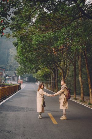 Foto de Pareja recién casada mostrando afecto y tomados de la mano mientras caminan a través del parque forestal nacional zhangjiajie en China
. - Imagen libre de derechos