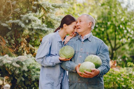 Photo for Senior with green gabbage. Brunette in a blue shirt. Grandfather with grandaughter. - Royalty Free Image