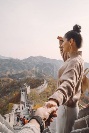 Foto de Hermosa chica sosteniendo su mano maridos en la Gran Muralla de China. Pareja recién casada en su honemoon a la Gran Muralla cerca de Beijing China. Elegante pareja explorando una de las maravillas del mundo - Imagen libre de derechos