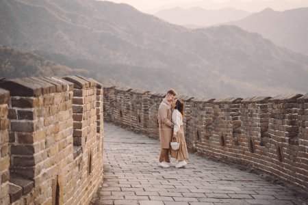 Foto de Hermosa pareja joven mostrando afecto en la Gran Muralla de China. Pareja recién casada en su honemoon a la Gran Muralla cerca de Beijing China. Elegante pareja explorando una de las maravillas del mundo - Imagen libre de derechos