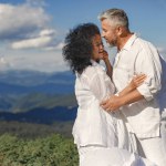 Senior man and woman in the mountains. Adult couple in love at sunset. Man in a white shirt.