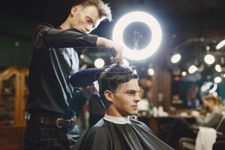 Der Mensch arbeitet mit Haaren. Friseur mit einem Kunden.