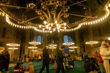 Téléchargez les photos : Les touristes et les habitants visitent Hagia Sophia, un magnifique chef-d'œuvre architectural situé à Istanbul, en Turquie, qui a servi d'église, de mosquée et de musée au cours des siècles. Avec son dôme planant, ses mosaïques complexes et sa riche histoire, il reste - en image libre de droit