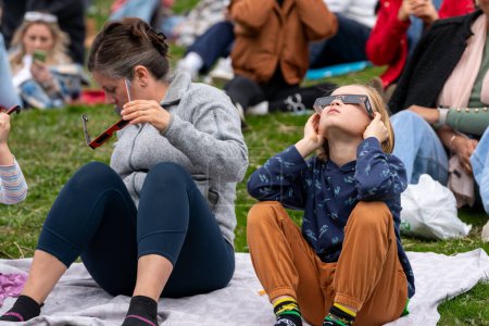Foto de Toronto, Canadá - 8 de abril de 2024: niño pequeño observando el comienzo del eclipse solar parcial en Riverdale Park, usando gafas de eclipse especiales. - Imagen libre de derechos