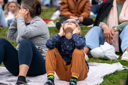 Foto de Toronto, Canadá - 8 de abril de 2024: niño pequeño observando el comienzo del eclipse solar parcial en Riverdale Park, usando gafas de eclipse especiales. - Imagen libre de derechos