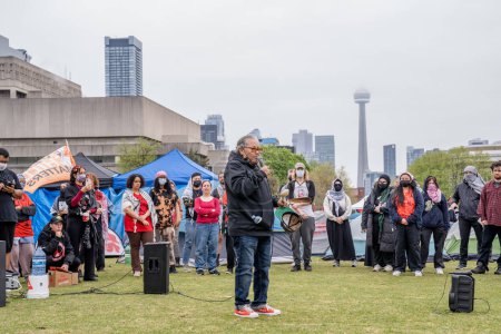 Téléchargez les photos : Une militante autochtone parle au nom de la Journée de la robe rouge, la Journée nationale de sensibilisation pour les femmes et les filles autochtones disparues et assassinées et les personnes bispirituelles, lors d'un campement créé par des étudiants occupant le cercle King College de l'Université de Torontos - en image libre de droit