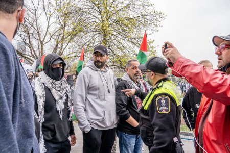 Foto de Estudiantes pro-palestinos forman una cadena humana, impidiendo que los manifestantes pro-Israel crucen, fuera del campamento que los estudiantes crearon al ocupar King College Circle en la Universidad de Toronto. - Imagen libre de derechos