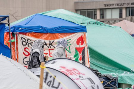 Téléchargez les photos : Signalisation et pulvérisation de messages pro-palestiniens sur des tentes peintes à l'Université de Toronto. Les étudiants occupent le campus avec un campement pro-palestinien, reflétant les mouvements mondiaux en faveur des droits palestiniens, tout en érigeant des barrières qui excluent - en image libre de droit