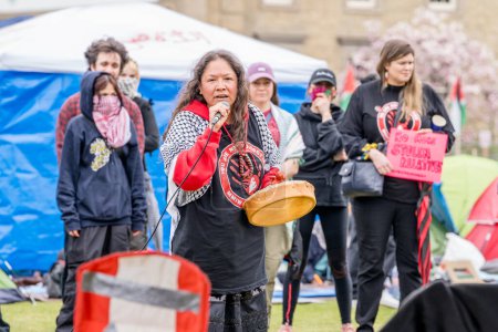 Foto de Activista indígena habla en nombre del Día del Vestido Rojo, el Día Nacional de Concientización sobre Mujeres y Niñas Indígenas Desaparecidas y Asesinadas y Personas de Dos Espíritus, en el campamento creado por estudiantes que ocupan el Círculo Universitario King College de la Universidad de Torontos - Imagen libre de derechos