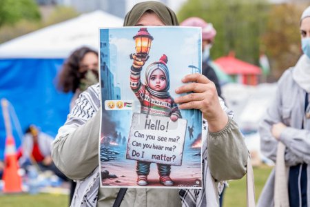 Photo for Pro-Palestinian activist holds up sign at encampment created by students occupying University of Torontos King College Circle. - Royalty Free Image