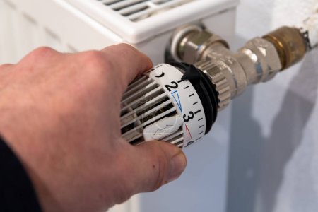 Male hand turns a radiator thermostat. High quality photo