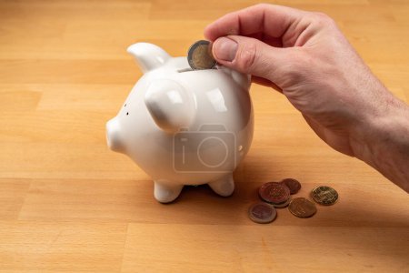 Photo for Hand puts euro coin into piggy bank. High quality photo - Royalty Free Image