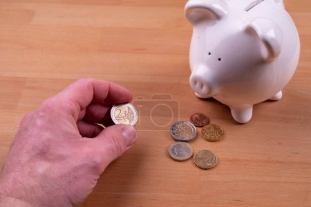 Foto de Piggy bank with male hand and some Euro coins. High quality photo - Imagen libre de derechos