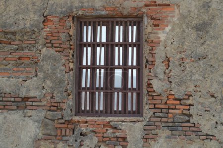 Téléchargez les photos : Ventana oxidada en una pared a medio interprétir y olvidada desgastada por el tiempo en la conocida zona de Puerto Colombia, Atlantico - en image libre de droit