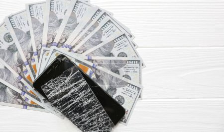 Photo for Broken screen protector tempered glass. Money lying near the phone. Dollar notes. - Royalty Free Image
