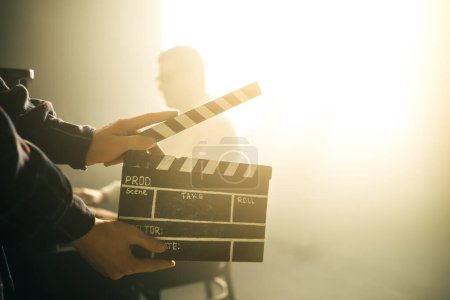 Photo for Clapperboard or clipboard in hands. Guy is directing and filming retro cinema or vintage movie. Composer man play on the old piano. - Royalty Free Image
