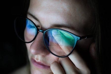 Müde Frau mit Brille arbeitet im Internet. Migräne oder Kopfschmerzen nach der Arbeit vor dem Computer den ganzen Tag. Augenschmerzen, Trockenheitssyndrom.