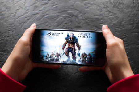 Téléchargez les photos : LVIV, UKRAINE - novembre 08, 2022 : Jouer au jeu mobile Assassin Creed : Valhalla sur smartphone moderne. - en image libre de droit
