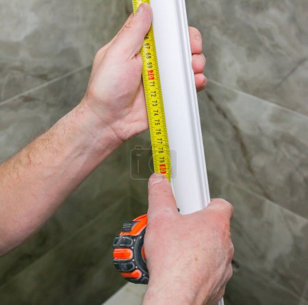 Foto de El hombre mide el zócalo de yeso. Mantenimiento obras de reparación renovación en el piso. Panel de paneles de yeso. - Imagen libre de derechos