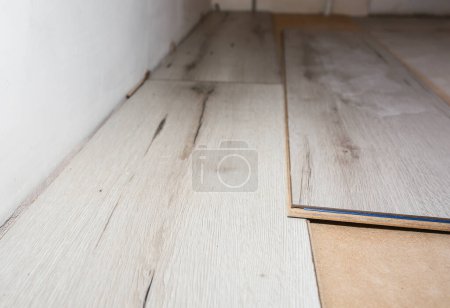 Laminate flooring in apartment. Maintenance repair works renovation. Restoration of wooden parquet planks indoors.
