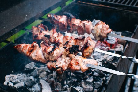 Photo for Frying meat pork on the grill. Shish kebab for summer party. Shashlik on wooden panels and open fire. - Royalty Free Image