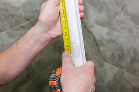 Foto de El hombre mide el zócalo de yeso. Mantenimiento obras de reparación renovación en el piso. Panel de paneles de yeso. - Imagen libre de derechos