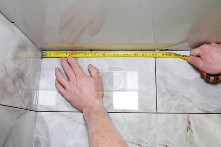 Foto de El hombre está midiendo el techo del zócalo de yeso. Mantenimiento obras de reparación renovación en el piso. Panel de paneles de yeso. - Imagen libre de derechos