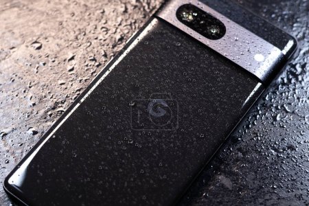 Téléchargez les photos : KYIV, UKRAINE - octobre 03, 2023 : Smartphone moderne Google Pixel avec des gouttes d'eau sur fond noir. Technologie moderne résistante à l'eau. - en image libre de droit
