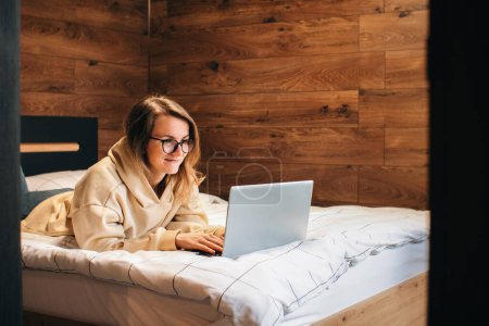 Freelancer woman working on bed with laptop. Good job.