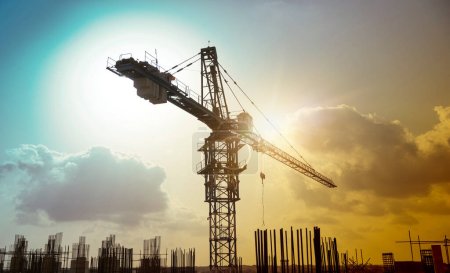 Large construction site including several cranes working on a silhouette complex, with cloudy background