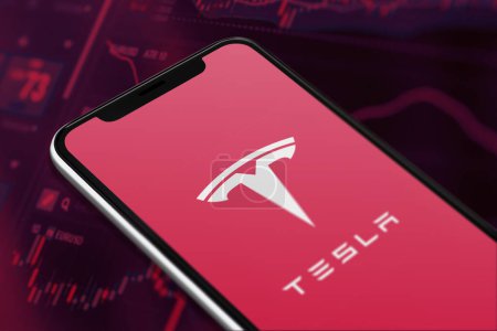 Téléchargez les photos : Karachi Pakistan - 12 juin 2023 : Logo Tesla sur l'écran du smartphone et le graphique du marché boursier à l'arrière-plan flou. - en image libre de droit