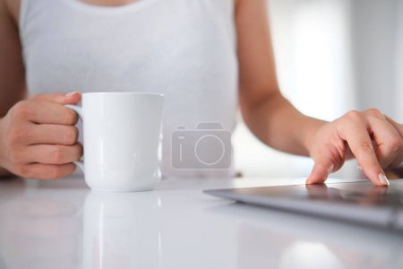 Foto de Vista lateral Mujer sosteniendo taza de café blanco, utilizando computer.Hands de mujer de negocios sobre fondo blanco - Imagen libre de derechos