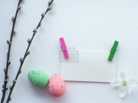 Photo for Happy Easter, white concept. Easter decorations on white background with copy space. Easter greating card. Flat lay. Willow twigs, green and pink eggs and apple flower. Celebrating Easter holidays. - Royalty Free Image