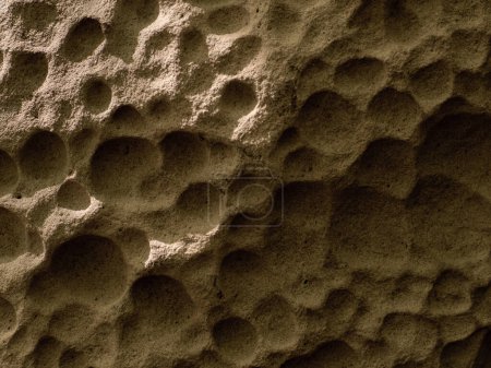 Natural stone It is shaped like a honeycomb hole. Weathered ancient stone covered in holes. Close up photo of the texture of a mountain rock. Film and grian simulation on processing.
