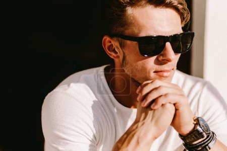 portrait of a brutal man in sunglasses and watch outdoors. Stylish man wearing casual. Mens beauty, fashion. Optics for men.
