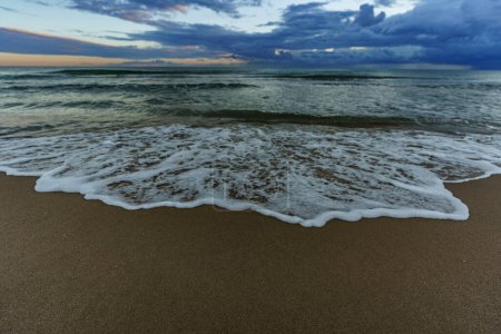 Téléchargez les photos : Des vagues de mer magnifiquement floues contre le rivage sablonneux de la mer - en image libre de droit