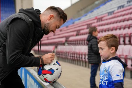Photo for Gwion Edwards #7 of Wigan Athletic signs an autograph as he arrives at the stadium before the Sky Bet Championship match Wigan Athletic vs Blackpool at DW Stadium, Wigan, United Kingdom, 12th November 202 - Royalty Free Image
