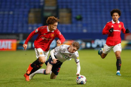 Photo for Sam Murray #79 of Manchester United tackles Conor Bradley #21 of Bolton Wanderers during the Papa John's Trophy match Bolton Wanderers vs Manchester United U21 at University of Bolton Stadium, Bolton, United Kingdom, 13th December 2022 - Royalty Free Image