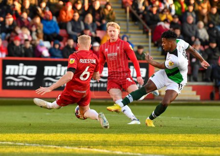 Photo for Plymouth Argyle forward Niall Ennis  (11) takes a shoot and is blocked by Cheltenham Town defender Lewis Freestone  (6)  during the Sky Bet League 1 match Cheltenham Town vs Plymouth Argyle at The Jonny-Rocks Stadium, Cheltenham, United Kingdom, 26th - Royalty Free Image