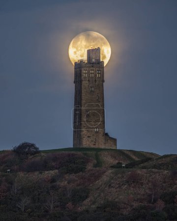 Photo for Wolf Moon sets at Victoria Tower Castle Hill near Huddersfield, West Yorkshire, United Kingdom, 6th January 202 - Royalty Free Image