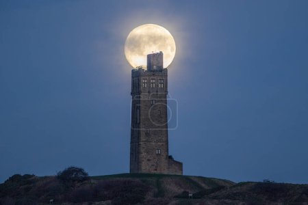 Photo for Wolf Moon sets at Victoria Tower Castle Hill near Huddersfield, West Yorkshire, United Kingdom, 6th January 202 - Royalty Free Image