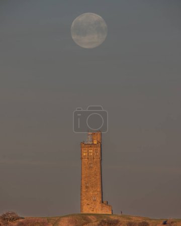 Photo for February's Snow Moon sets at Victoria Tower, Castle Hill near Huddersfield, United Kingdom, 6th February 2023 - Royalty Free Image