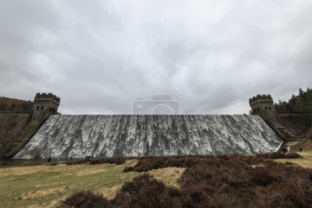 Photo for Derwent Dam overflows as Derwent reservoir fills up after months of drought. The dam is where RAF 617 Squadron practiced their the low-level flights needed for Operation Chastise during World War Two. Derwent reservoir, Bamford, United Kingdom - Royalty Free Image