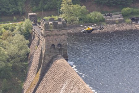 Photo for A RAF Juno helicopter flys over Derwent Dam on the Dambusters 80th anniversary. The 16th May 2023 marks the 80th anniversary of Operation Chastise, better known as the Dambusters Raid; Derwent Dam, Bamford, United Kingdom - Royalty Free Image