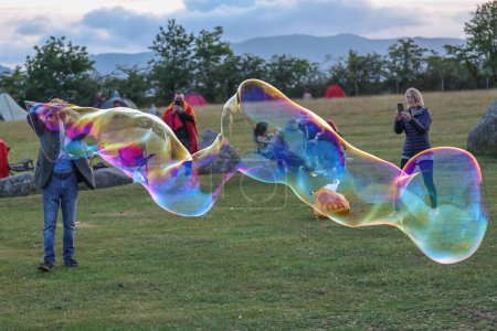 Photo for A person blows bubbles as he entertains people in the centre of the stone circle during the Castlerigg Stone Circle Summer Solstice Celebration, United Kingdom, 20th June 2023 - Royalty Free Image