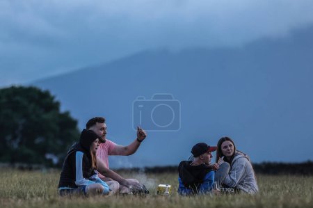 Téléchargez les photos : Les gens s'assoient et se refroidissent au coucher du soleil pendant la célébration du solstice d'été du Cercle de pierre de Castlerigg, Royaume-Uni, 20 juin 2023 - en image libre de droit