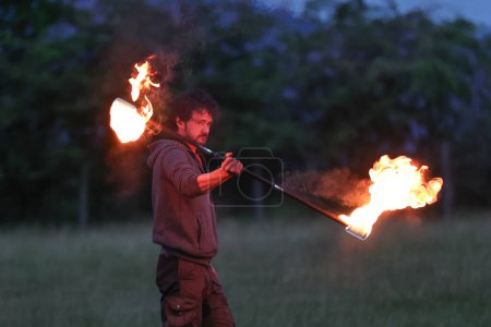 Téléchargez les photos : Un participant fait tournoyer un bâton de feu pendant qu'il divertit les spectateurs pendant la célébration du solstice d'été du Cercle de pierre de Castlerigg, Royaume-Uni, 20 juin 2023 - en image libre de droit